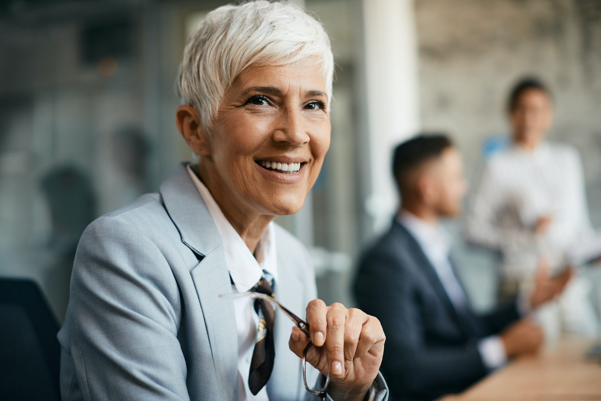 Happy senior businesswoman working at corporate office and looking at camera.